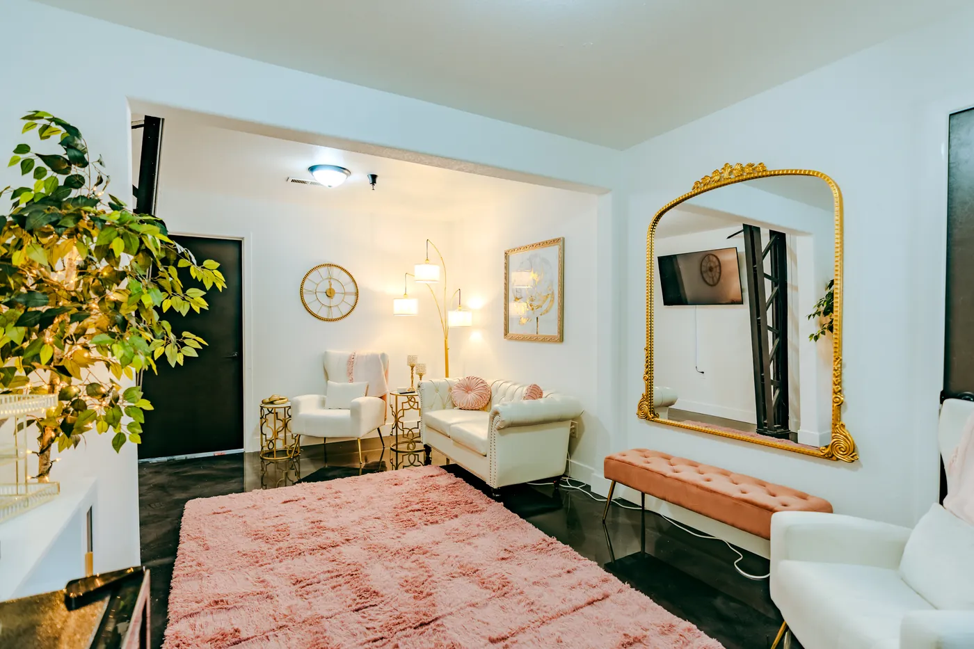 The Loft 102 bridal suite with a pink rug, white chairs and a gold mirror