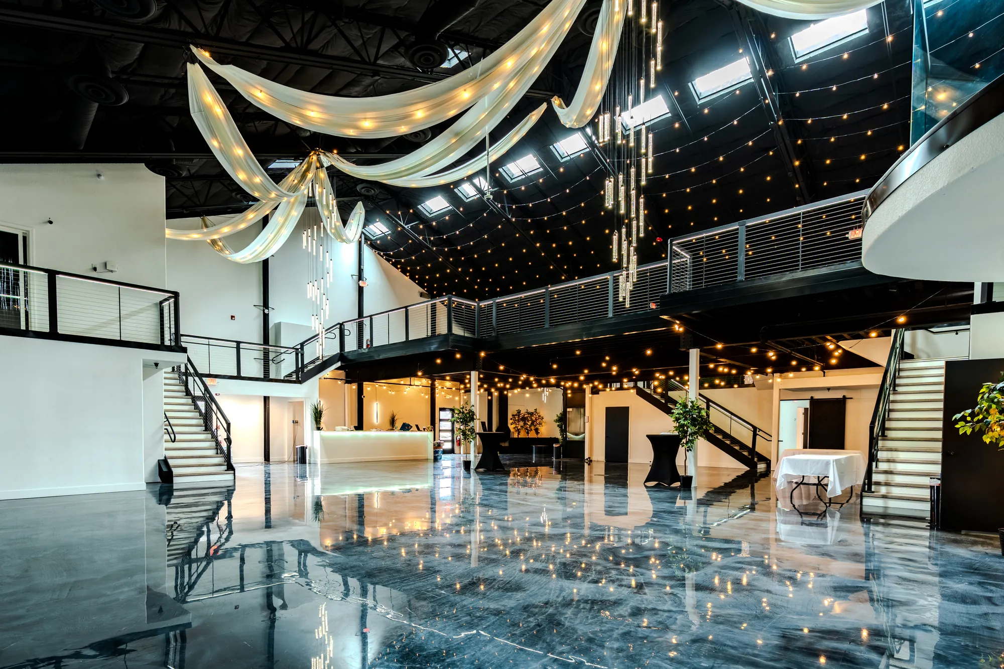 The Loft 102 event hall with draped ceiling, string lights, a mezzanine and a glossy floor
